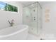 Bright bathroom featuring a soaking tub and a glass-enclosed shower with marble tile at 4562 Rockford Ct, Charlotte, NC 28209