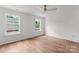 Minimalist bedroom with hardwood floors, two windows providing plenty of natural light, and a modern ceiling fan at 4562 Rockford Ct, Charlotte, NC 28209