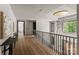 Hallway featuring hardwood flooring, a modern chandelier, and sleek railings leading to the lower level at 5432 Carmel Rd, Charlotte, NC 28210