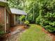Back view of brick home with screened in porch, trees, grass and pathway in backyard at 5816 Valley Stream Trl, Waxhaw, NC 28173