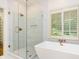 Bathroom featuring a glass shower, free-standing soaking tub, and large window at 5816 Valley Stream Trl, Waxhaw, NC 28173