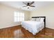 Comfortable bedroom with hardwood floors, a ceiling fan, and plantation shutters at 5816 Valley Stream Trl, Waxhaw, NC 28173