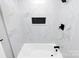 Bright bathroom with white marble-look tiles and modern matte black fixtures surrounding a white bathtub at 5953 Prescott Ct # 3105, Charlotte, NC 28269
