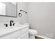 Clean bathroom features white vanity with sink, toilet, mirror and black fixtures and towel bar at 5953 Prescott Ct # 3105, Charlotte, NC 28269