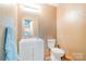 Powder room features a white vanity and toilet, with textured walls for a unique touch at 7545 Rabbit Cir, Denver, NC 28037