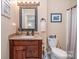 Cozy bathroom with a wood vanity, granite countertop, decorative mirror, and a framed art print at 7545 Rabbit Cir, Denver, NC 28037