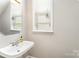 A half bath features a white pedestal sink, neutral walls, and a window with blinds at 7642 Rolling Meadows Ln, Huntersville, NC 28078