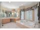 This bathroom has a garden tub, a vanity, carpeted floors, lots of mirrors, custom curtains, and natural light at 8800 Covey Rise Ct, Charlotte, NC 28226