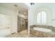 Serene bathroom with tiled shower, soaking tub with a shuttered arched window and tile floors at 9202 Arlington Hills Dr, Mint Hill, NC 28227