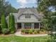 A charming home exterior features a front porch framed by manicured landscaping and brick and siding accents at 9202 Arlington Hills Dr, Mint Hill, NC 28227