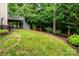 The backyard features a grassy slope with lush trees, offering a serene and private outdoor space at 9410 Greenbank Ct, Charlotte, NC 28214