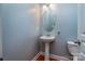 Powder room with pedestal sink, oval mirror and wood-look floors at 9410 Greenbank Ct, Charlotte, NC 28214