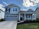 Charming two-story home with gray siding, stone accents, a covered porch, and a two-car garage at 1016 Laggan Ln, Indian Trail, NC 28079