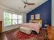 Bright main bedroom with a sloped ceiling, blue accent wall, and a large window with natural light at 10639 Secret Garden Ln, Charlotte, NC 28214