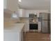 Well-lit kitchen features stainless steel appliances, white cabinets, and wood-look flooring at 1111 Balcorn Pl, Charlotte, NC 28214