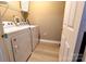 Bright laundry room with white washer and dryer units, shelving, and modern flooring at 11867 Ridgeway Park Dr, Charlotte, NC 28277