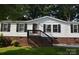 View of the front entrance of the home, showing stairs leading up to a dark-stained door and vinyl siding at 14335 Saint Johns Dr # 83, Stanfield, NC 28163