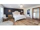 Primary bedroom featuring a decorative chandelier, hardwood floors, a black accent wall, and a walk-in bath at 16132 Mclester Rd, Oakboro, NC 28129