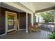 Inviting front porch with rocking chairs and a warm welcome sign by the wooden-trimmed glass door at 16132 Mclester Rd, Oakboro, NC 28129