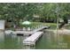 Picturesque waterfront dock with a boat, seating, and a charming bridge to the backyard at 18118 Pompano Pl, Cornelius, NC 28031