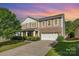 Charming two-story home with a two-car garage, manicured lawn, and colorful sky at sunset at 1905 Yellow Daisy Dr, Matthews, NC 28104