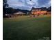 Evening shot of a spacious backyard with a pool, fire pit area, and a well-lit home, perfect for relaxation at 205 Wingate Dr, Stanley, NC 28164