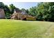 Beautifully landscaped backyard with an expansive lawn, complemented by mature trees, a large deck, and covered porch at 2168 Sunset Cir, Fort Mill, SC 29715