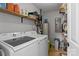Functional laundry room featuring a washer, dryer, shelving, and a water heater for household needs at 223 Tennessee Trl, Lincolnton, NC 28092