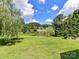 View of a grassy backyard with a pond and trees, with a house in the distance at 2325 Perry Rd, Denver, NC 28037