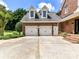 Spacious three-car garage with white doors and additional exterior door, framed by brick and well-kept landscaping at 2325 Perry Rd, Denver, NC 28037