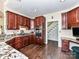 Well-lit kitchen featuring dark wood cabinetry, stainless steel appliances, and a view to the staircase at 2325 Perry Rd, Denver, NC 28037