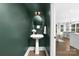 Stylish half bathroom with green walls, pedestal sink, and view to the home's living areas at 2517 Marlowe Ave, Charlotte, NC 28208