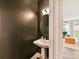 Stylish half bathroom with modern fixtures, a pedestal sink, and dark accent wall at 2517 Marlowe Ave, Charlotte, NC 28208