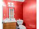 Compact bathroom featuring a single sink vanity, toilet, and bright red walls at 2809 Waycross Dr, Monroe, NC 28110