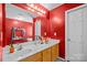 Bathroom featuring red walls, double sinks, and bright lighting above the vanity mirror at 2809 Waycross Dr, Monroe, NC 28110