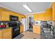 Well-equipped kitchen with wood cabinets, black appliances, and a view into the adjacent dining area at 2809 Waycross Dr, Monroe, NC 28110