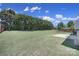 Large backyard featuring green grass, a wooden fence and bordered by mature trees and a rear patio at 3015 Liddington Rd, Matthews, NC 28105