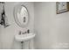 Cozy powder room featuring a pedestal sink, decorative mirror, neutral paint and elegant decor at 3015 Liddington Rd, Matthews, NC 28105