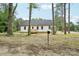 View of a white, single-story home with a wooden porch, nestled between mature trees at 403 W Charlotte Ave, Mount Holly, NC 28120