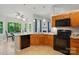 Kitchen with wood cabinets and black appliances adjacent to a sunny breakfast nook at 4612 Saxonbury Way, Charlotte, NC 28269