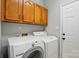 Laundry room with washer, dryer, overhead cabinets, and a door at 4612 Saxonbury Way, Charlotte, NC 28269