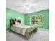 Green bedroom features a queen bed, window view of trees, and neutral-colored carpet for a peaceful space at 5005 Hedgebrook Ln, Waxhaw, NC 28173