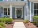 Inviting front porch featuring a navy door with sidelights, white columns, and lush landscaping around the walkway at 5005 Hedgebrook Ln, Waxhaw, NC 28173