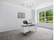 Bright home office featuring a modern desk, neutral carpet, and a large window with views of the front yard at 5005 Hedgebrook Ln, Waxhaw, NC 28173