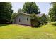 View of home's gray siding and a well-maintained grassy backyard with mature trees at 517 Powell St, Rock Hill, SC 29732