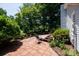 Patio area with brick pavers, exterior hose hookup and garden surrounded by lush landscaping at 517 Powell St, Rock Hill, SC 29732
