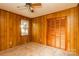 Carpeted bedroom with wood-paneled walls, a ceiling fan, a window overlooking the backyard, and closet at 661 Blackwelder Rd, Statesville, NC 28625