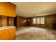 Spacious living room featuring wood paneling, a fireplace, large windows, and neutral carpeting at 661 Blackwelder Rd, Statesville, NC 28625