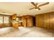 Open-concept living room with wood paneling, large windows, and a ceiling fan, with adjacent kitchen at 661 Blackwelder Rd, Statesville, NC 28625