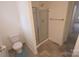 Modern bathroom featuring a glass-enclosed shower, a toilet, and a neutral-toned tile floor at 6919 Ware Rd, Charlotte, NC 28212